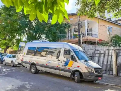 Uma van da agência de viagens parceira estacionada estrategicamente em frente ao Refúgio Hostel Fortaleza & Pousada, pronta para levar nossos hóspedes a um passeio incrível rumo às belas praias de Águas Belas, no litoral cearense. Este é um dos muitos serviços que oferecemos para tornar a estadia de nossos visitantes ainda mais completa e memorável. Com a conveniência de embarcar diretamente na porta do Refúgio, nossos hóspedes aproveitam o conforto e a praticidade de explorar Fortaleza e arredores com tranquilidade. A rua arborizada e calma em frente ao nosso hostel e pousada adiciona um charme especial à experiência de quem escolhe ficar conosco.